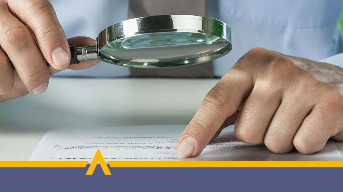 Osoba analizuje treści dokumentu przy użyciu lupy
