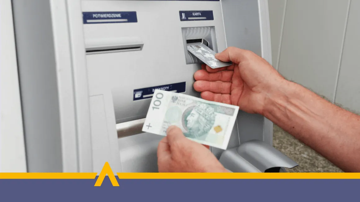 Osoba wypłacająca gotówkę z bankomatu – karta płatnicza i banknot 100 zł